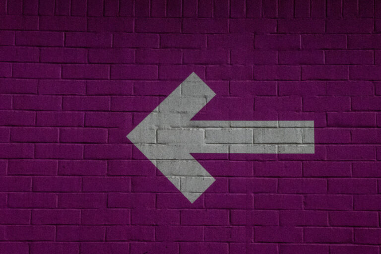 white arrow on purple brick wall